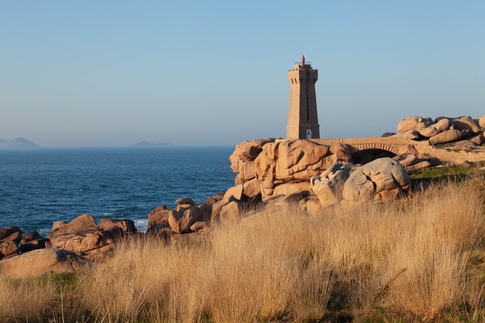 Faro storico sulle scogliere di granito delle isole Scilly al tramonto Faro storico sulle scogliere di granito delle isole Scilly al tramonto