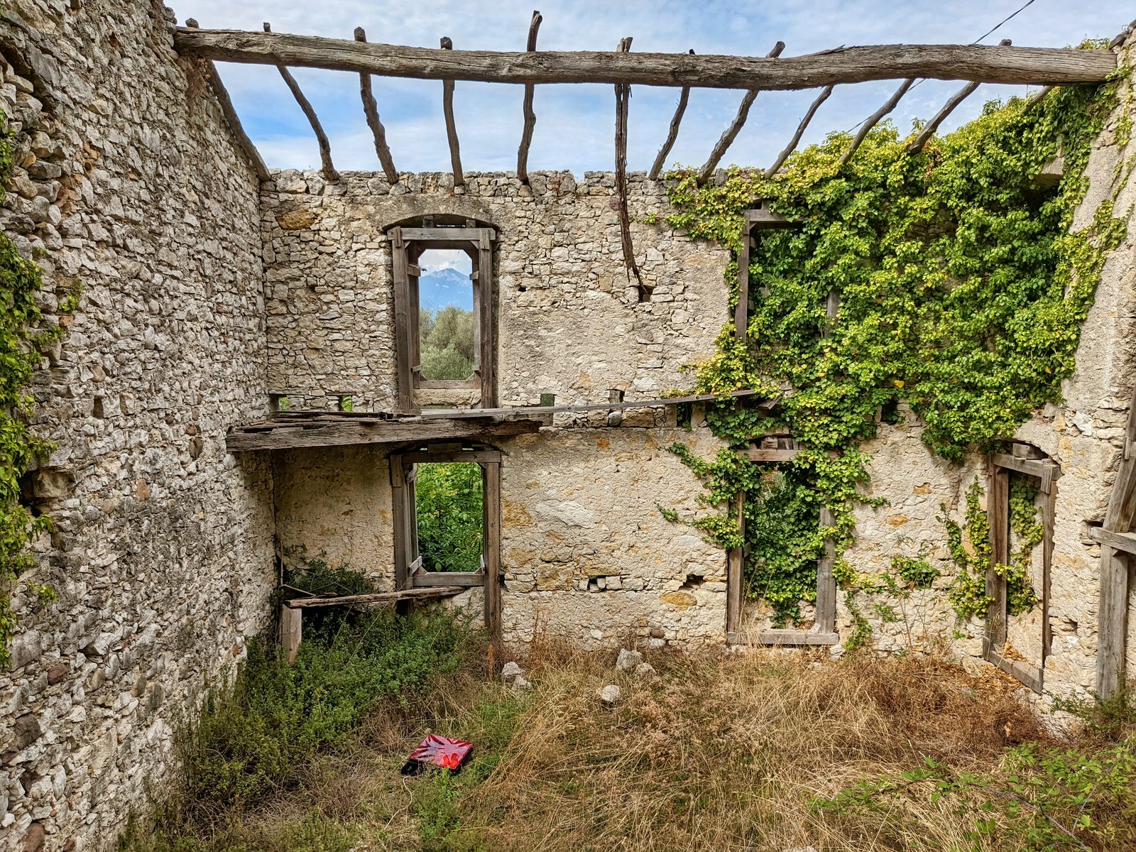 Interno di una casa abbandonata con muri di pietra a secco e vegetazione che cresce tra le macerie Interno di una casa abbandonata con muri di pietra a secco e vegetazione che cresce tra le macerie