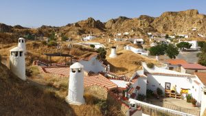 Camini bianchi delle case-grotta emergono dalle colline di tufo rosso di Guadix, Andalusia