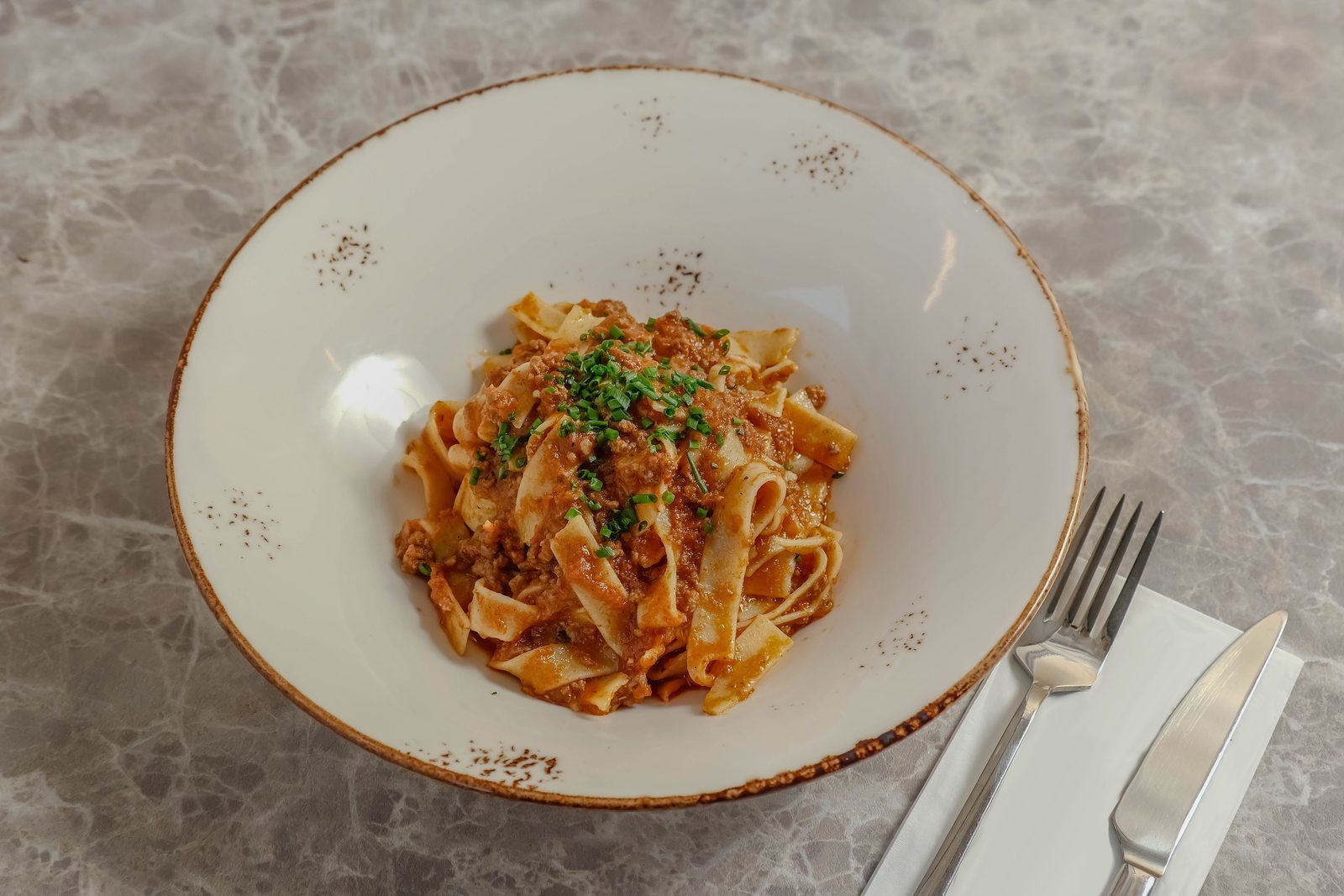 Piatto tipico pugliese con ragù di carne su tavolo in pietra rustico