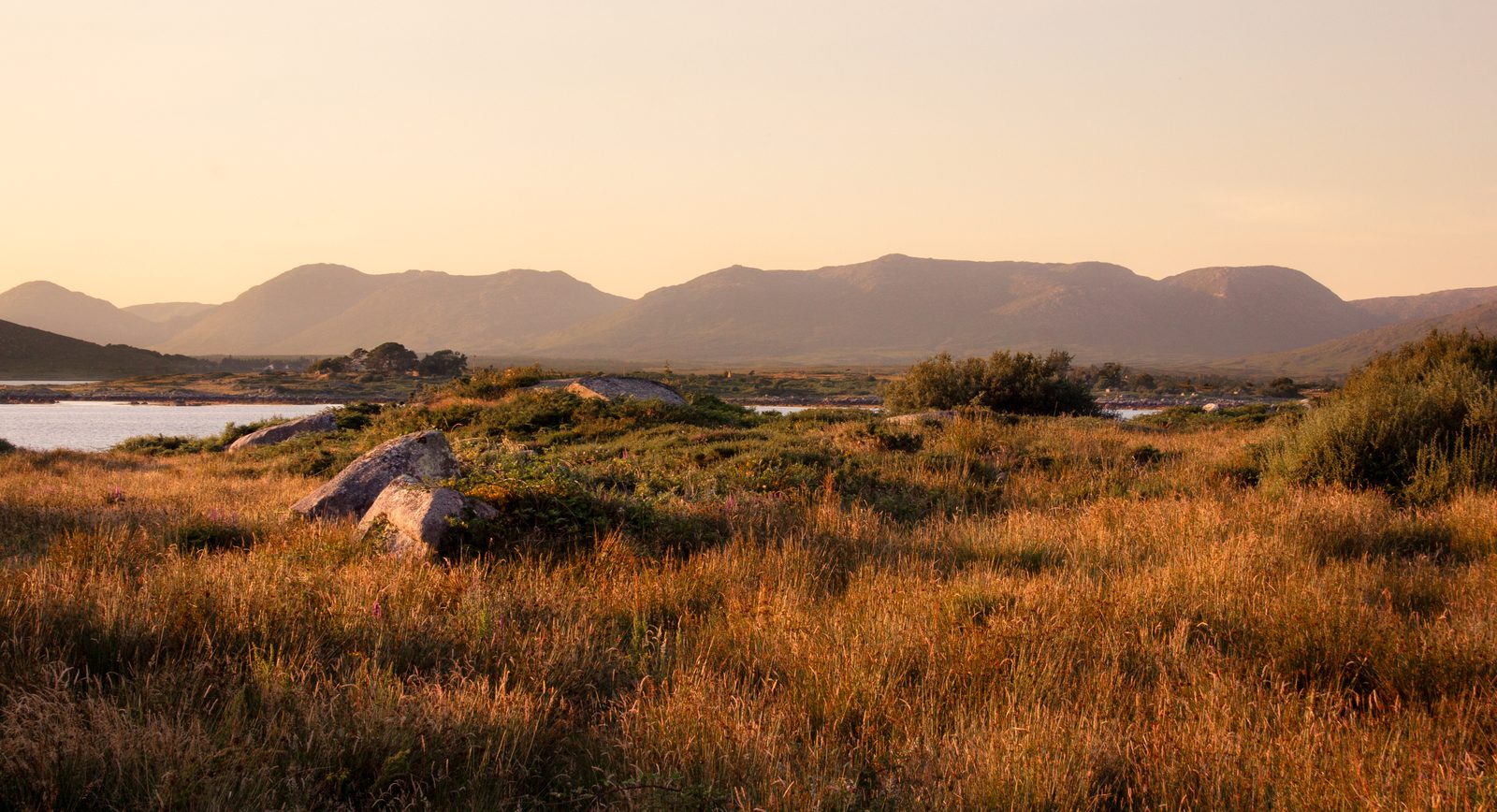 Paesaggio di torbiera e montagne del Connemara al tramonto con colori ramati